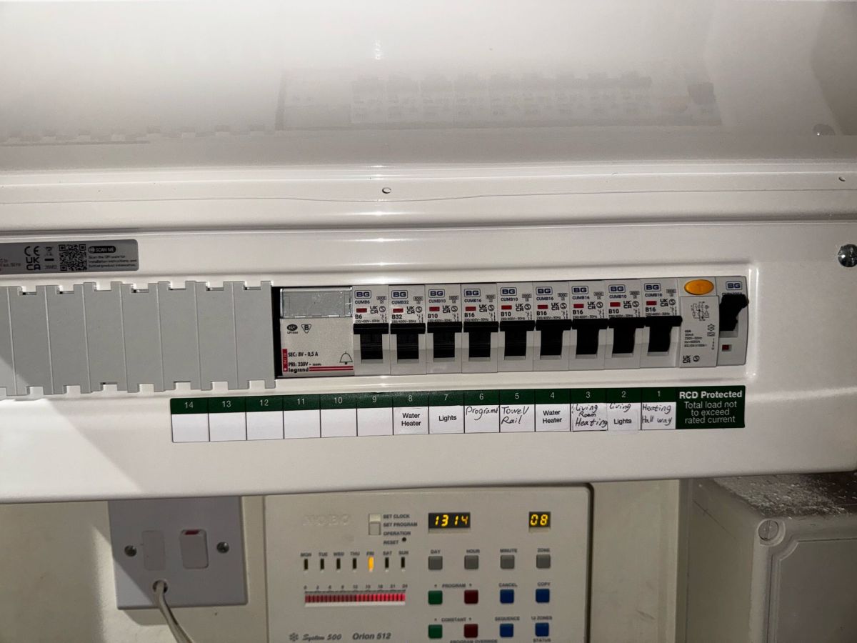 RCD-protected consumer unit supplying lighting, water heater and electric heating circuits above a heating programmer