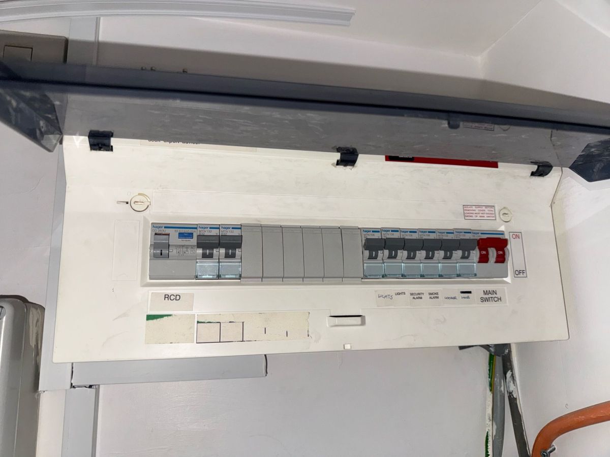 Older Hager consumer unit with a single RCD, blanked spare ways and a security-alarm circuit, lid open for inspection